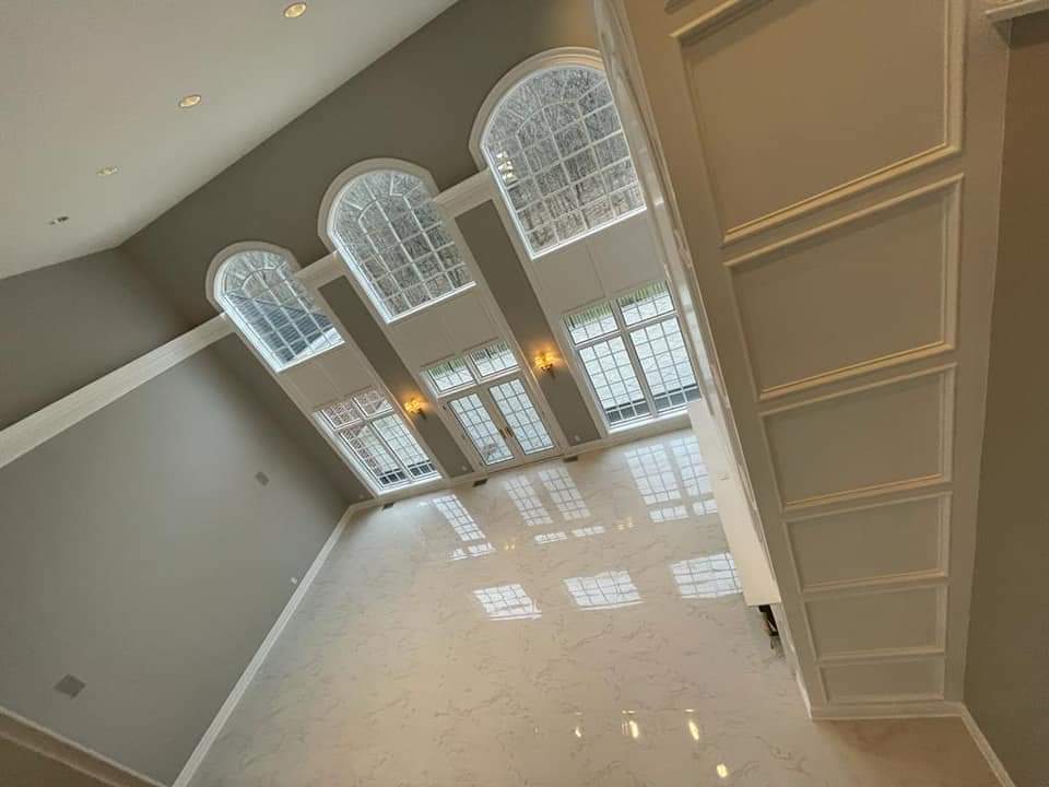 High-angle view of a large room with arched windows, light-colored walls and flooring, and decorative molding.