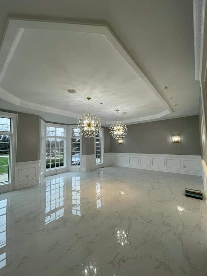 Empty room with white marble floors, two globe chandeliers, and large windows.