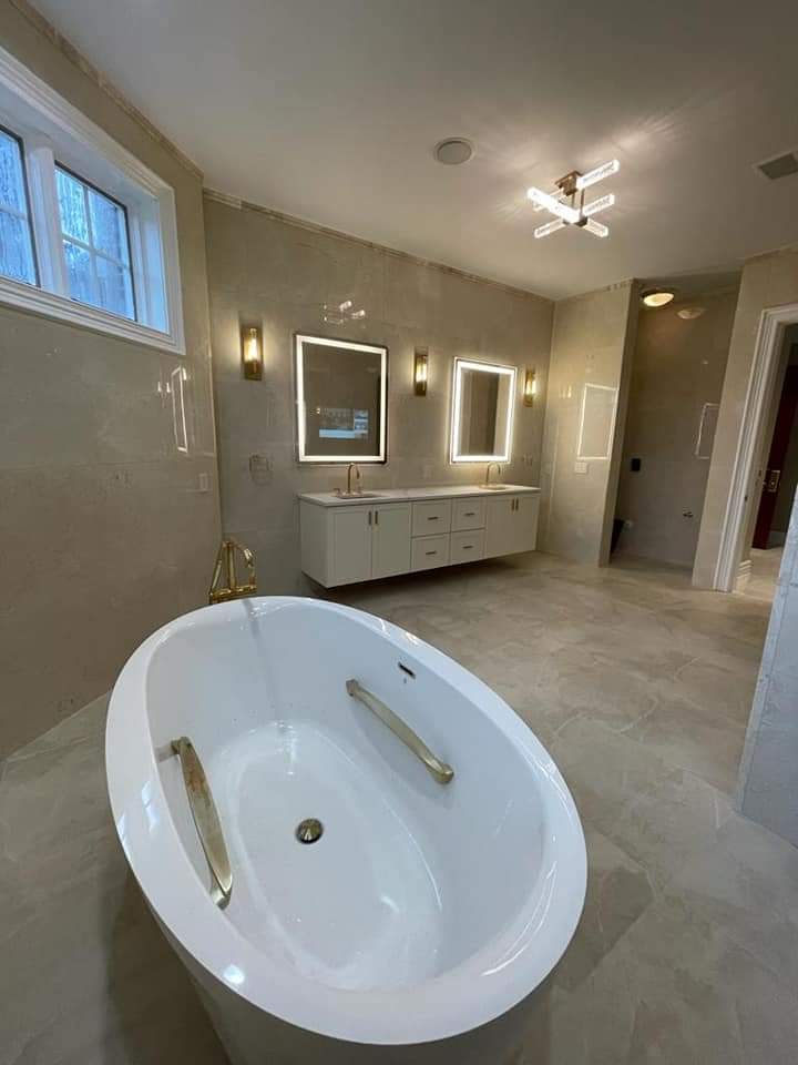 Modern bathroom with an oval bathtub, double vanity, and gold fixtures.