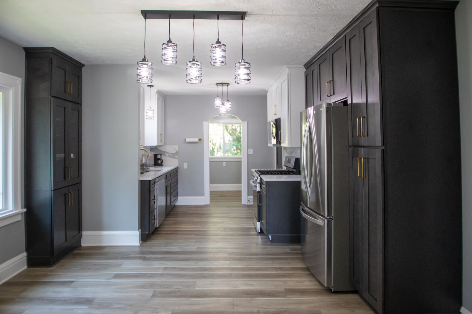 Modern kitchen with gray walls, dark cabinets, stainless steel appliances, and pendant lights.