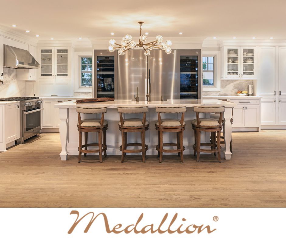 Bright white kitchen with island, stainless steel appliances, and wood flooring. 
