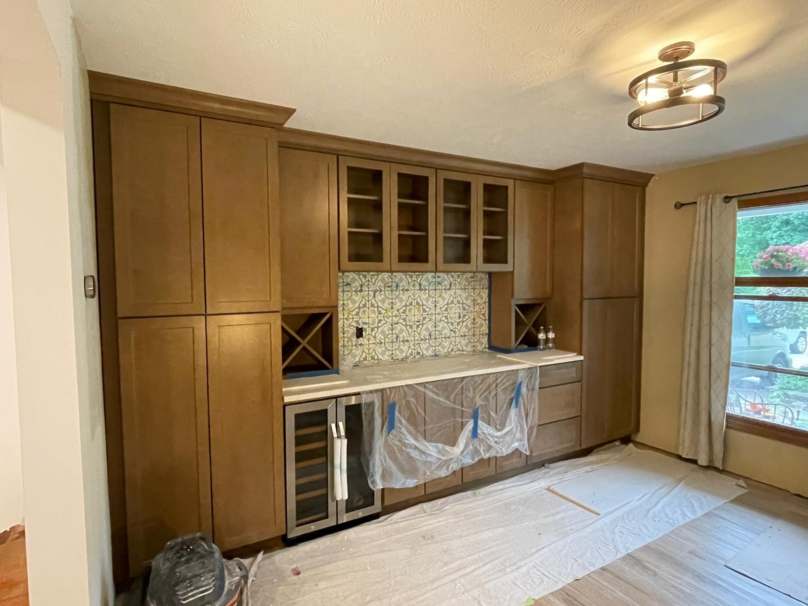 New built-in cabinetry in a room, featuring a wine fridge, storage, and a mosaic tile backsplash.
