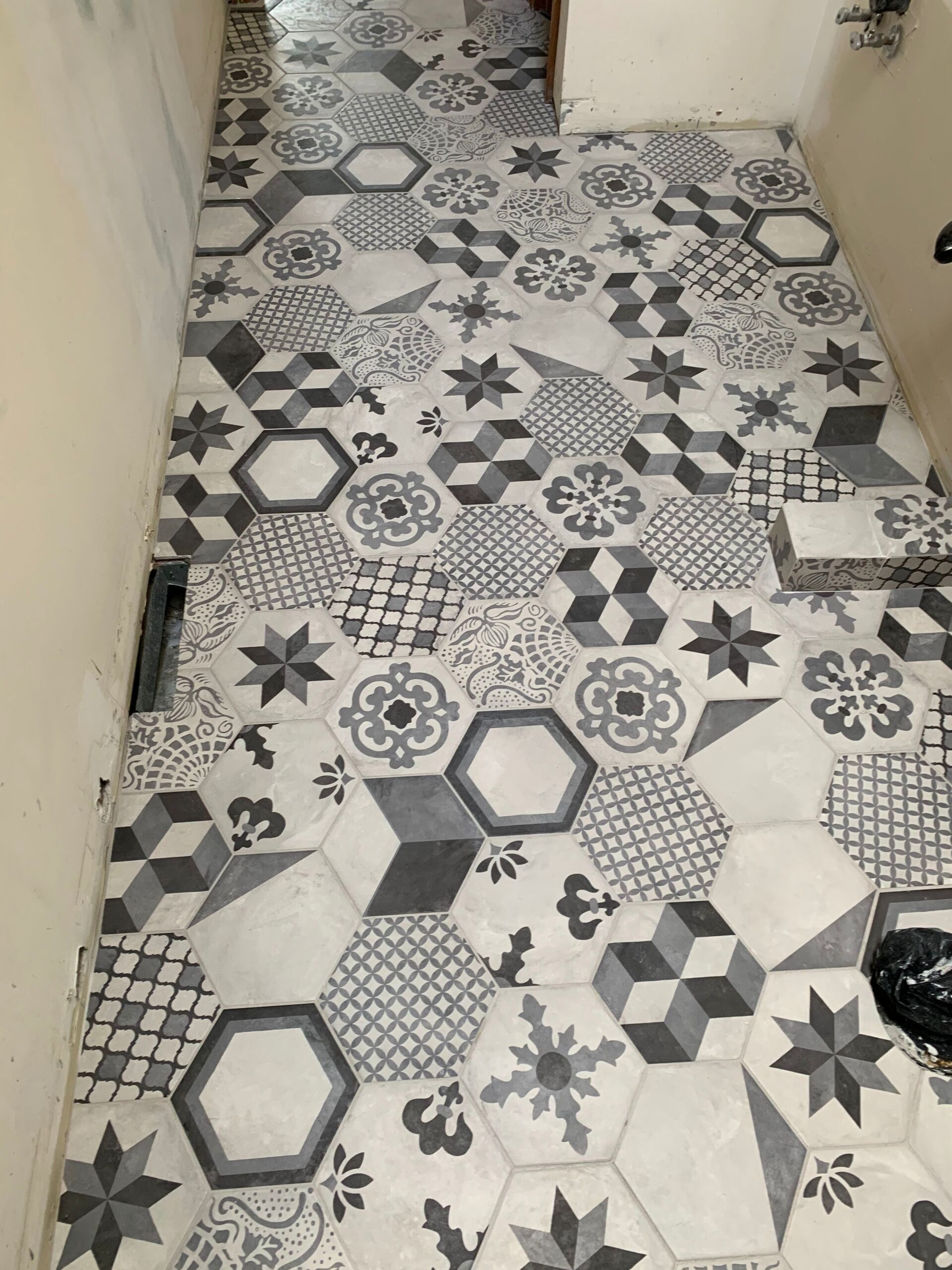 Tiled floor with hexagon patterns in gray and white.  Partial installation in a narrow room.