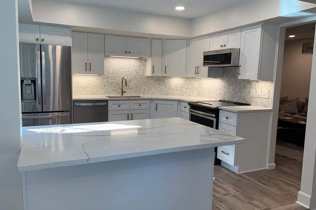Modern kitchen with white cabinets, stainless steel appliances, and a quartz countertop.
