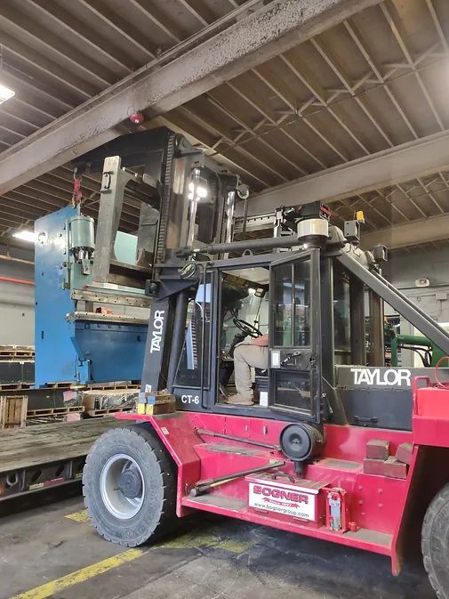 A Red Forklift is Carrying a Blue Machine in a Warehouse | Wooster, OH | Bogner Construction Company