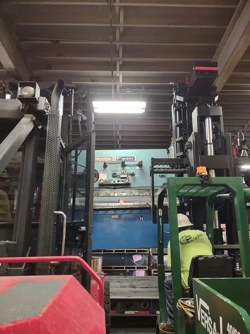 A Man is Sitting in a Green Forklift in a Warehouse | Wooster, OH | Bogner Construction Company