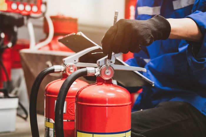 A man is fixing a fire extinguisher in a garage.