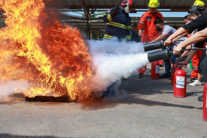 A group of firefighters are using fire extinguishers to put out a fire.