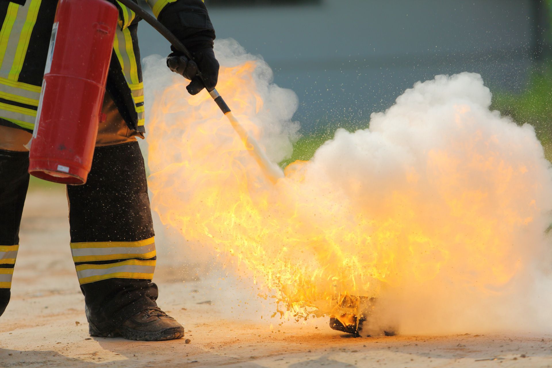 A fireman is using a fire extinguisher to put out a fire.