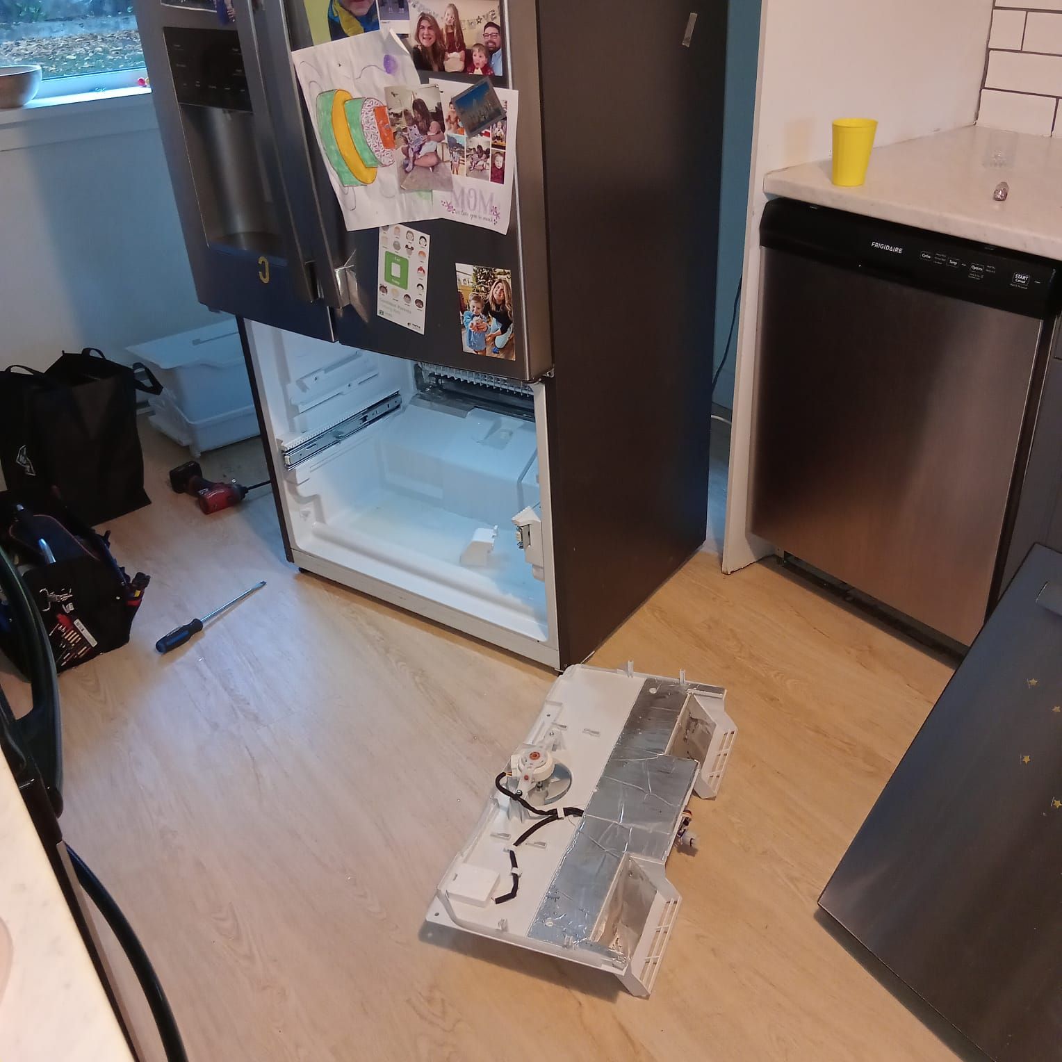 The fridge with the bottom door removed being repaired.