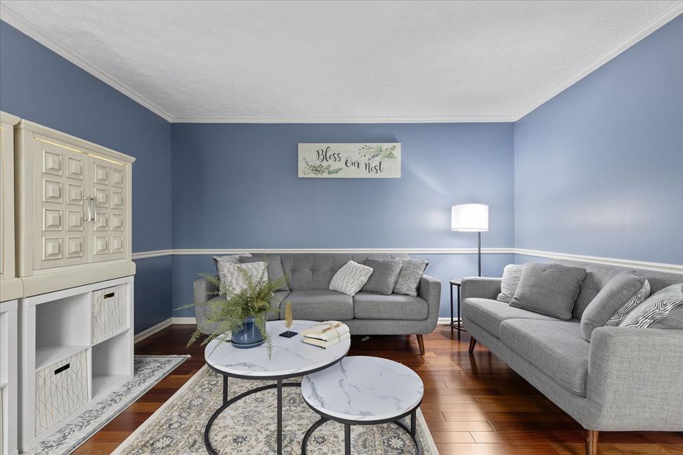 Living room with blue walls, gray couches, marble coffee tables, and hardwood floors.