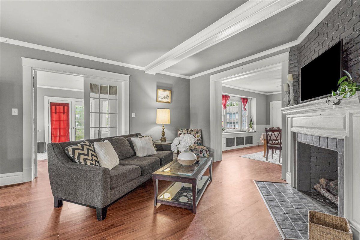 Living room with gray walls, sofa, fireplace, and open doorway to dining room and red door.