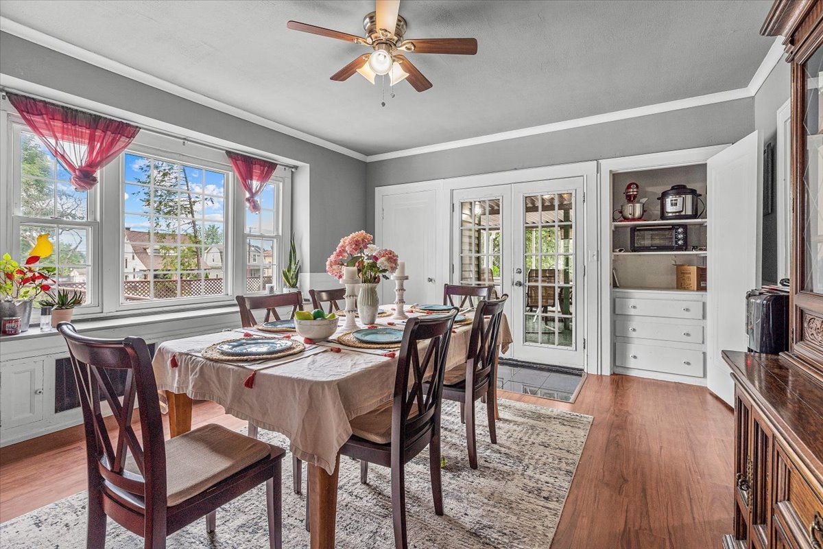 Dining room with table set for a meal, large windows, and a built-in cabinet.
