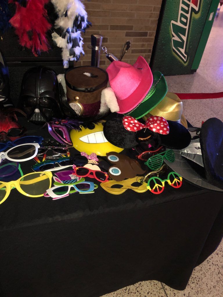 Photo booth props on a table: sunglasses, hats, masks, and a Darth Vader mask.