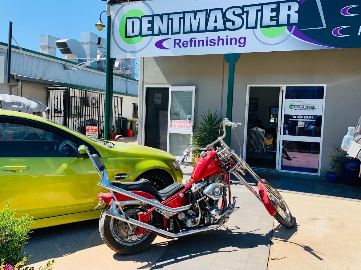 A Red Motorcycle is Parked in Front of a Dentmaster Refinishing Store — Dentmaster Refinishing In Bungalow, QLD