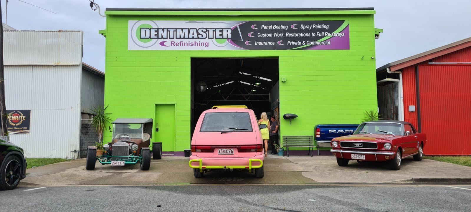 A Pink Car is Parked in Front of a Green Building — Dentmaster Refinishing In Bungalow, QLD