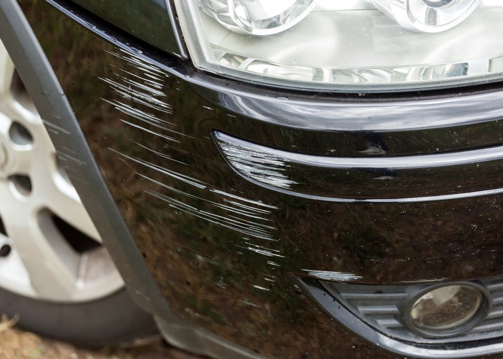A Close Up of a Black Car With a Scratch on the Front Bumper — Dentmaster Refinishing In Bungalow, QLD