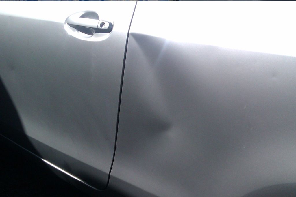 A Close Up of a Car With a Damaged Door — Dentmaster Refinishing In Bungalow, QLD