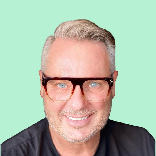 Man with graying hair wearing glasses, smiling against a light green background.