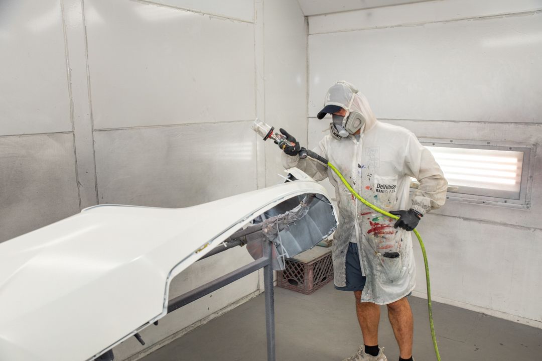 Painting a car part at Town Line Auto Body