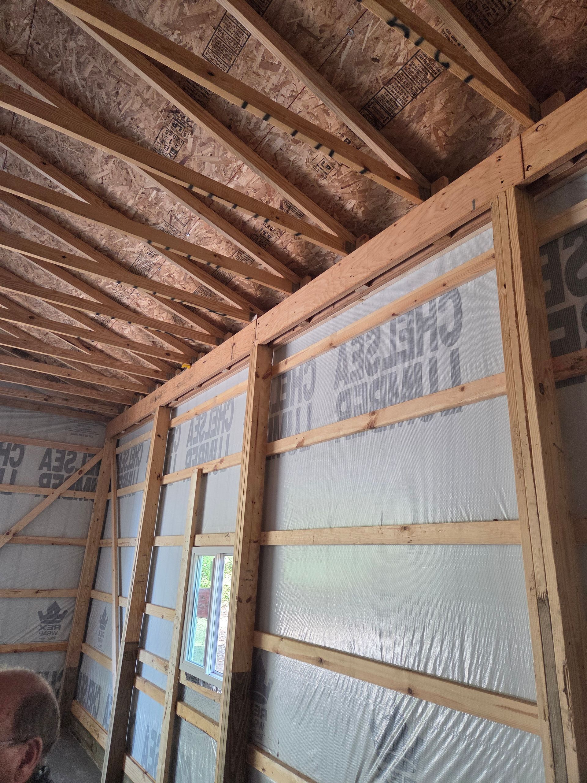 Interior of a building under construction, wooden frame with insulation and exposed roof beams.