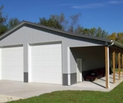 Gray metal garage with two white garage doors and an attached covered porch, blue sky.