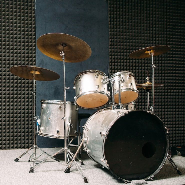 Drum set in a soundproof room with cymbals and a dark-colored bass drum.