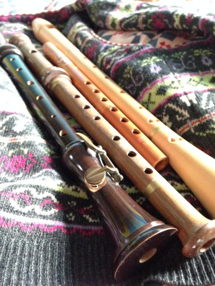 Four wooden recorders on a patterned sweater.