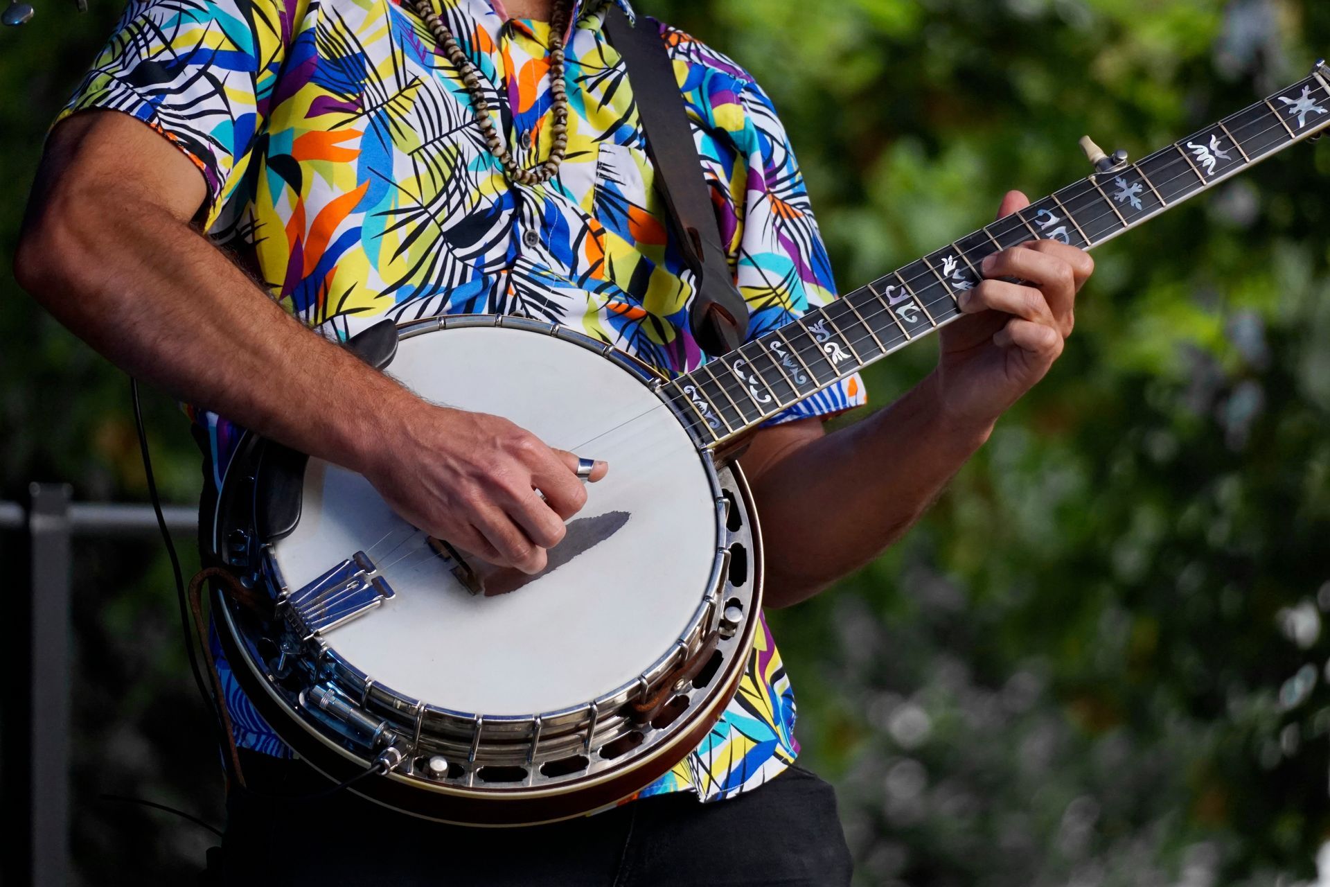 A banjo ukulele with a wooden neck and body, metal rim, and taut skin drumhead.