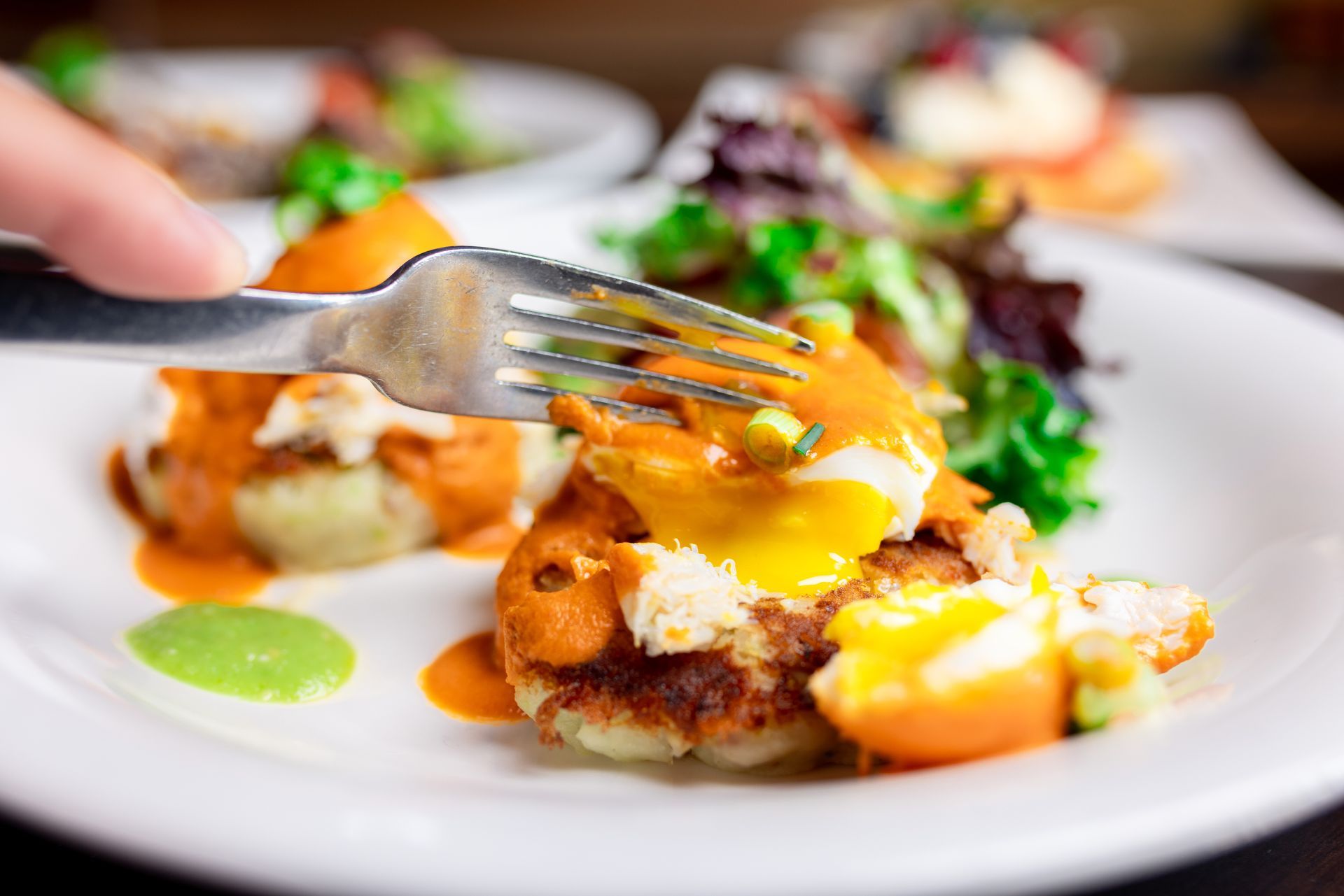 A person is holding a fork over a plate of food.