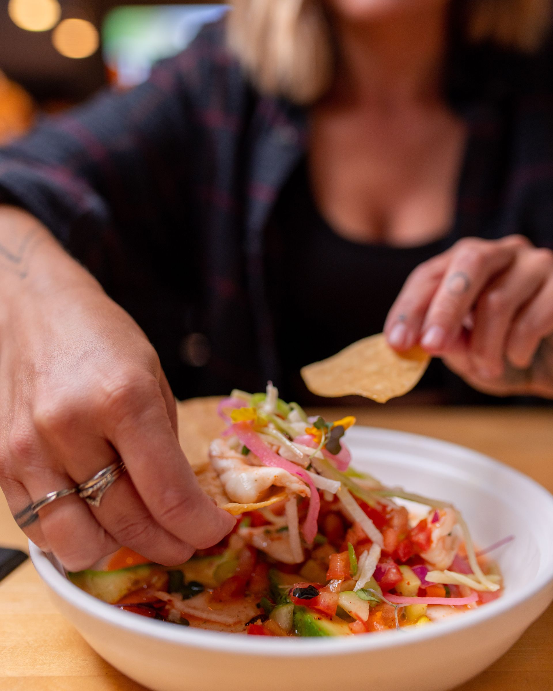 A woman is eating a bowl of food with a fork.
