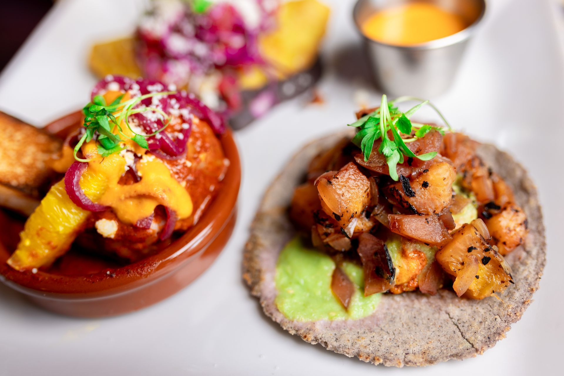 A plate of food with two tacos and a bowl of food on a table.
