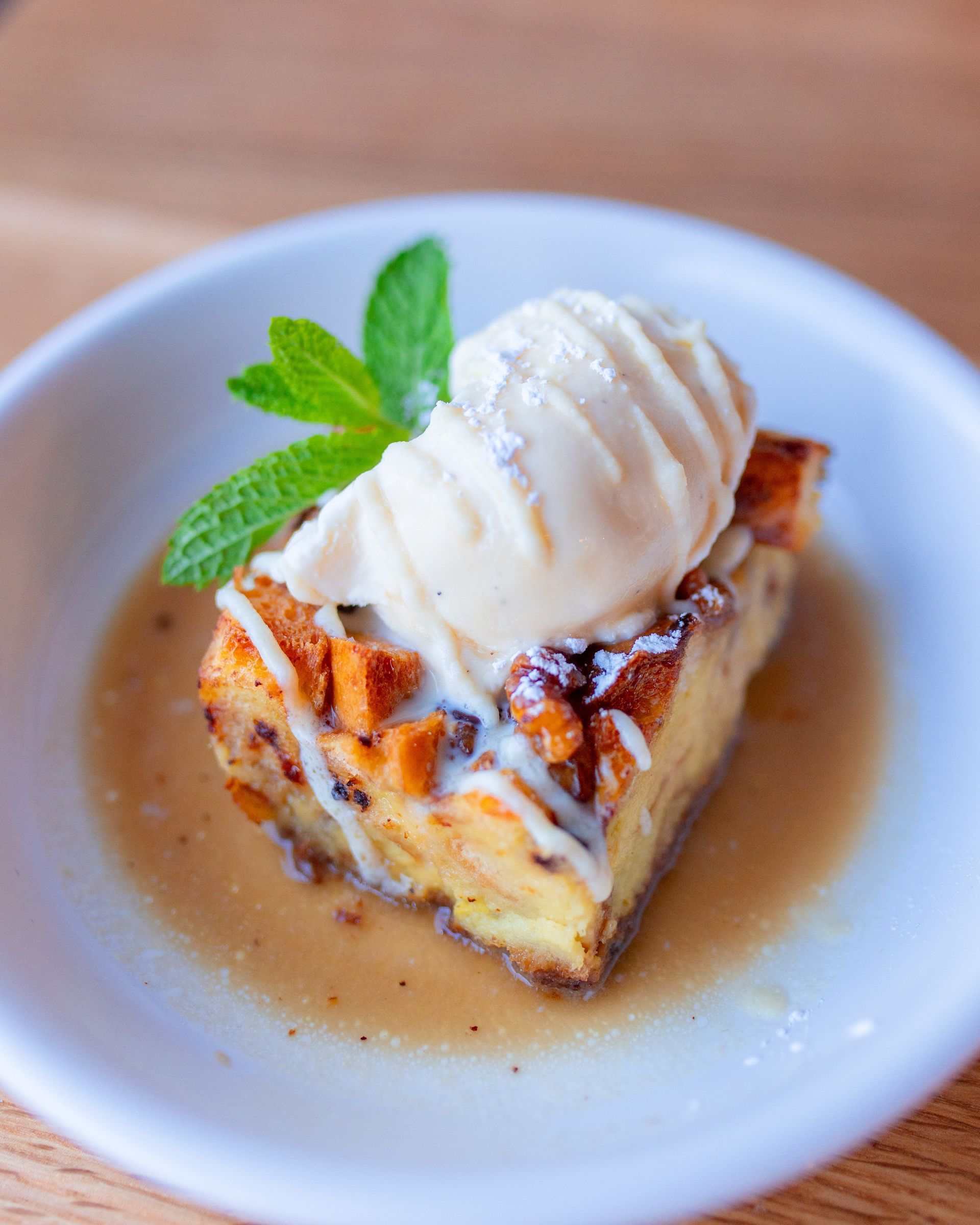 A piece of bread pudding with ice cream on top on a plate.