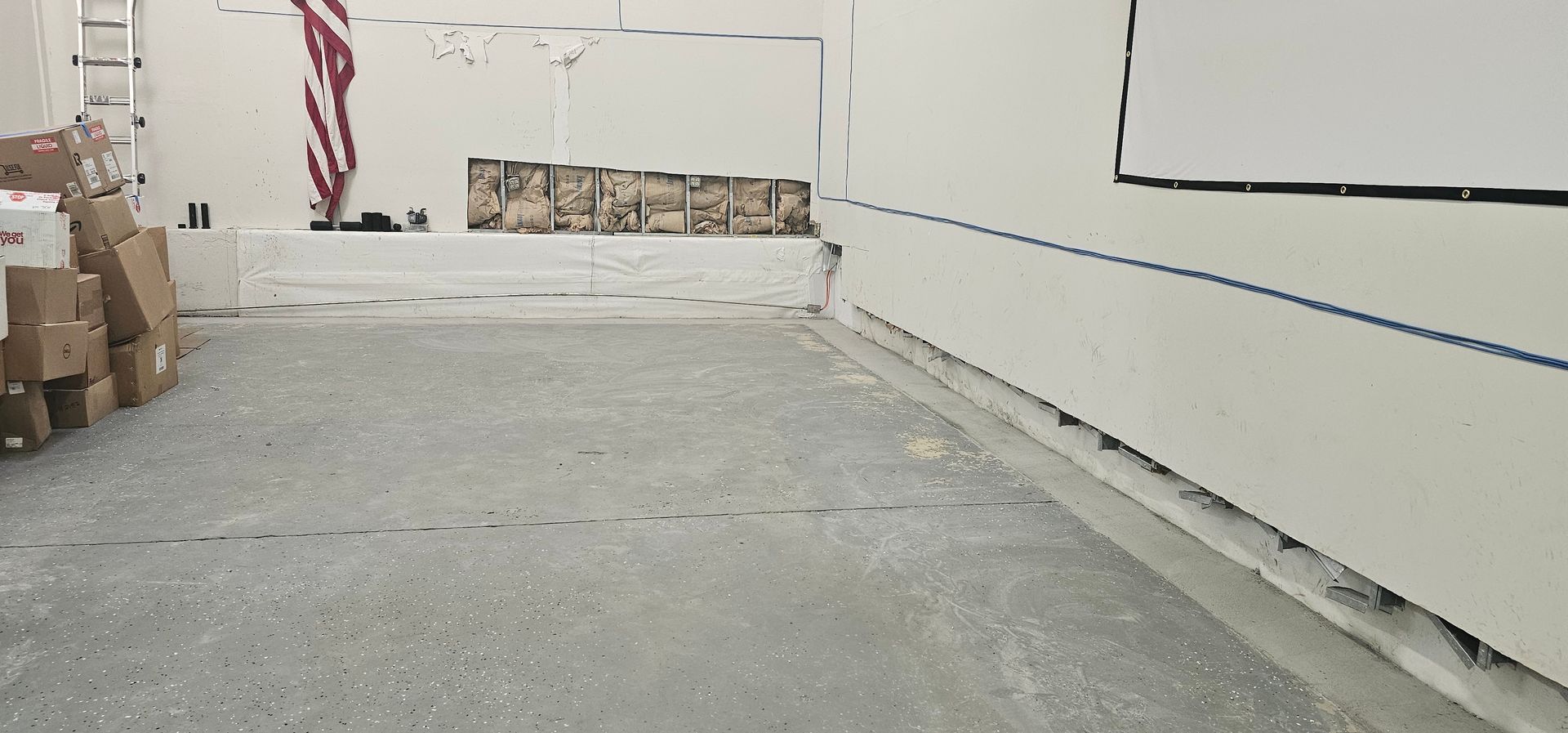 A room with boxes on the floor and a white board on the wall