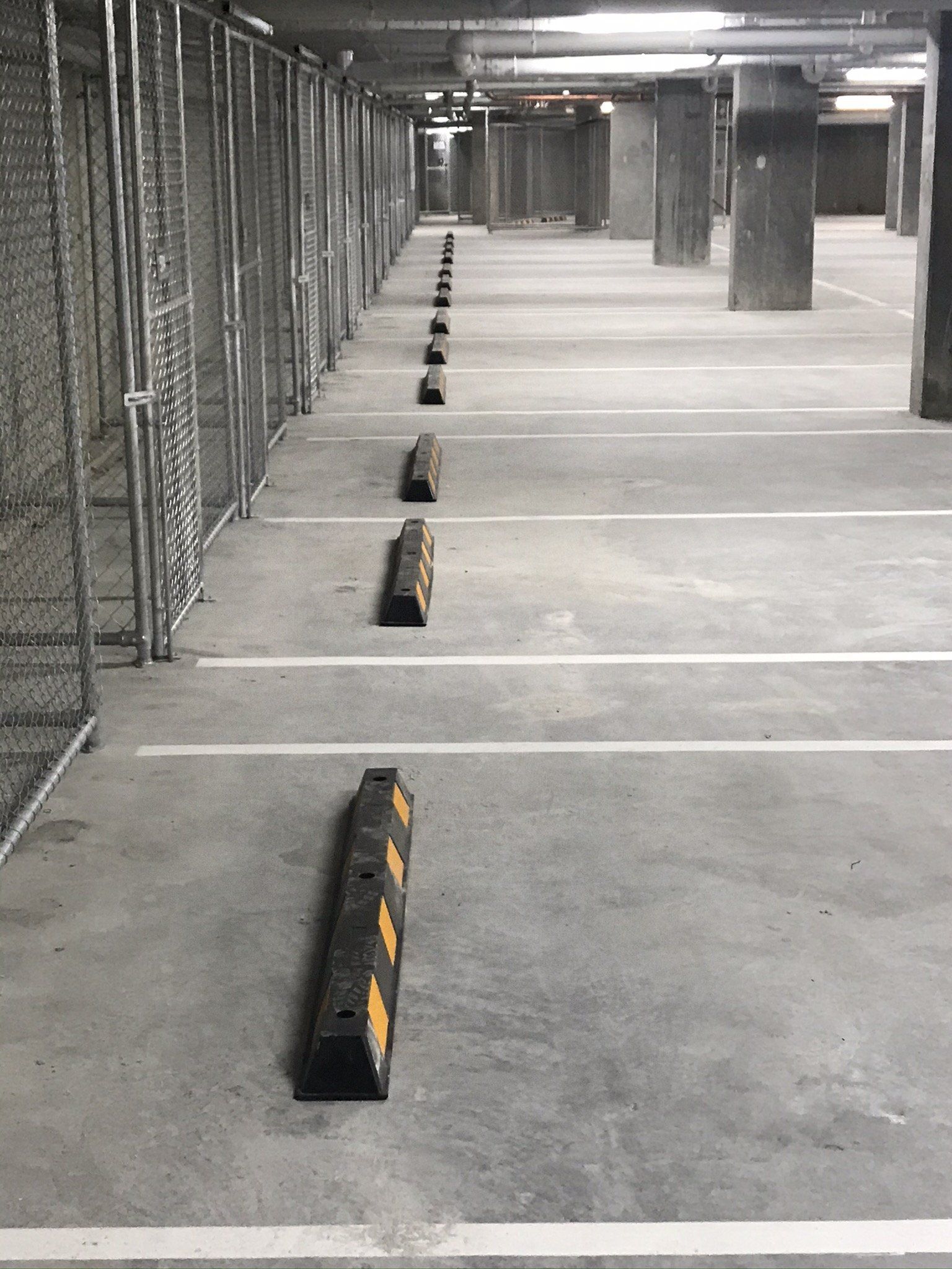 Row of black and yellow rubber wheel stops in a basement car park
