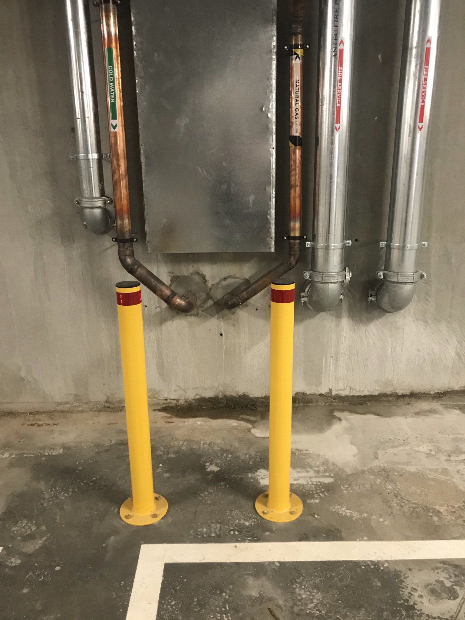 Yellow bollards protecting important services in a basement car park