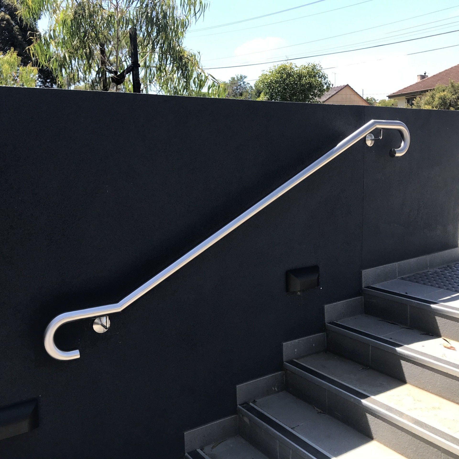 Wall mounted stainless steel handrail to assist with walking down a set of stairs