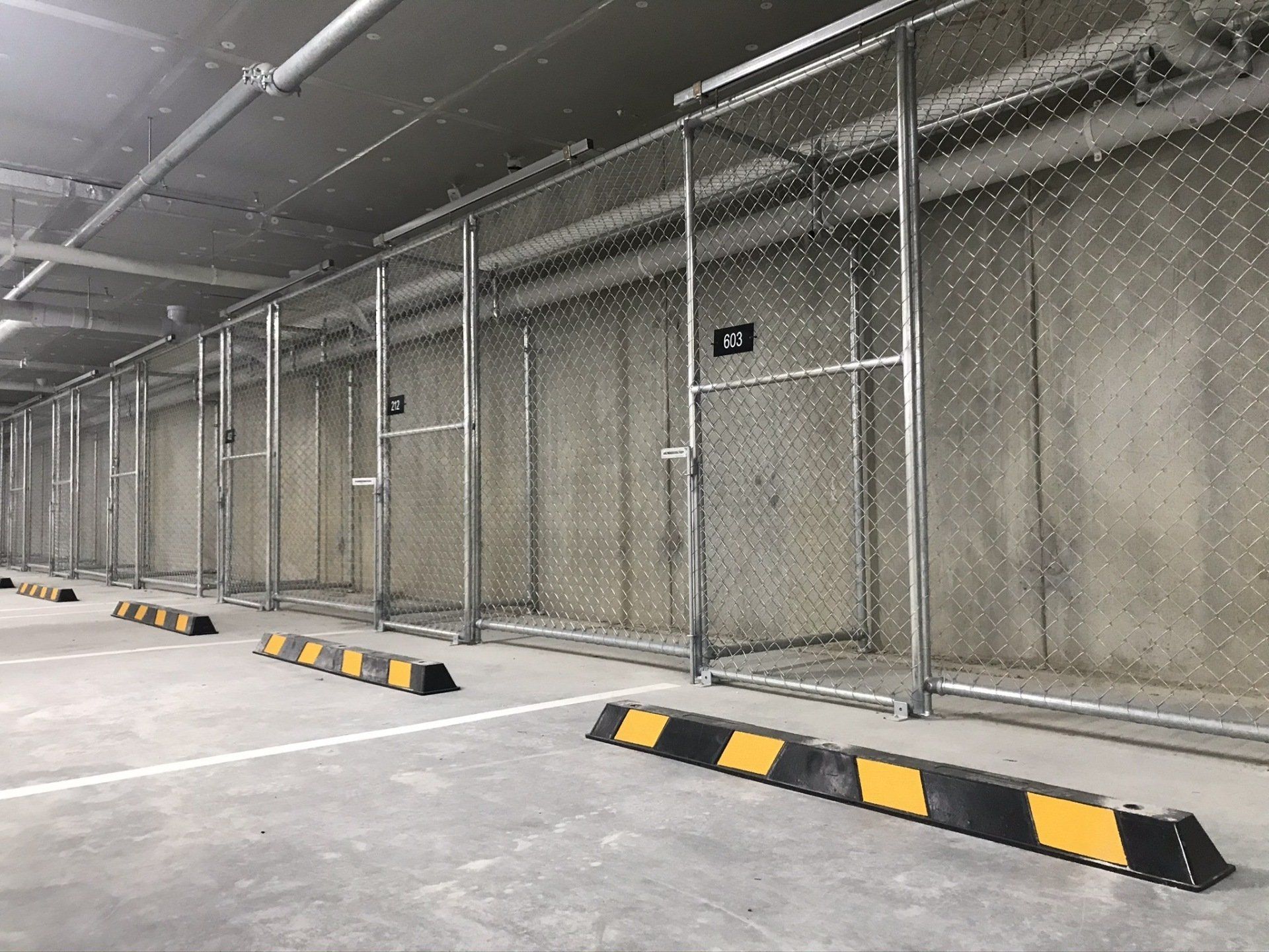 Row of chain mesh storage cages with sliding gates