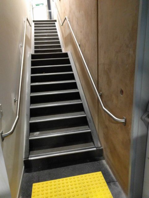Stainless steel handrails wall mounted on either side of a long set of stairs