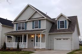 Two-story house with a gray exterior, white porch, and a garage. Gray siding and dark roof.