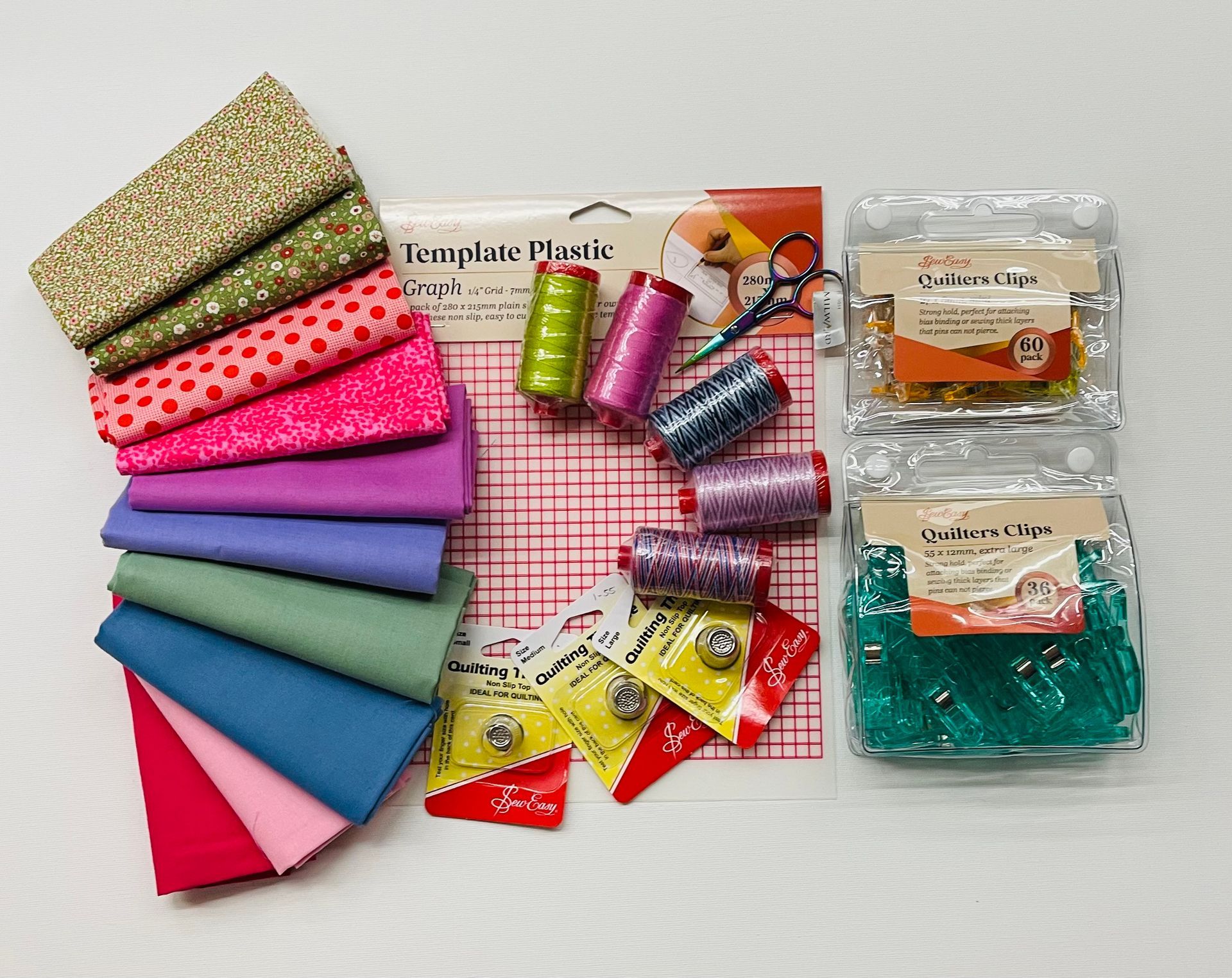 A collection of spring sewing supplies including spools of thread pins and scissors