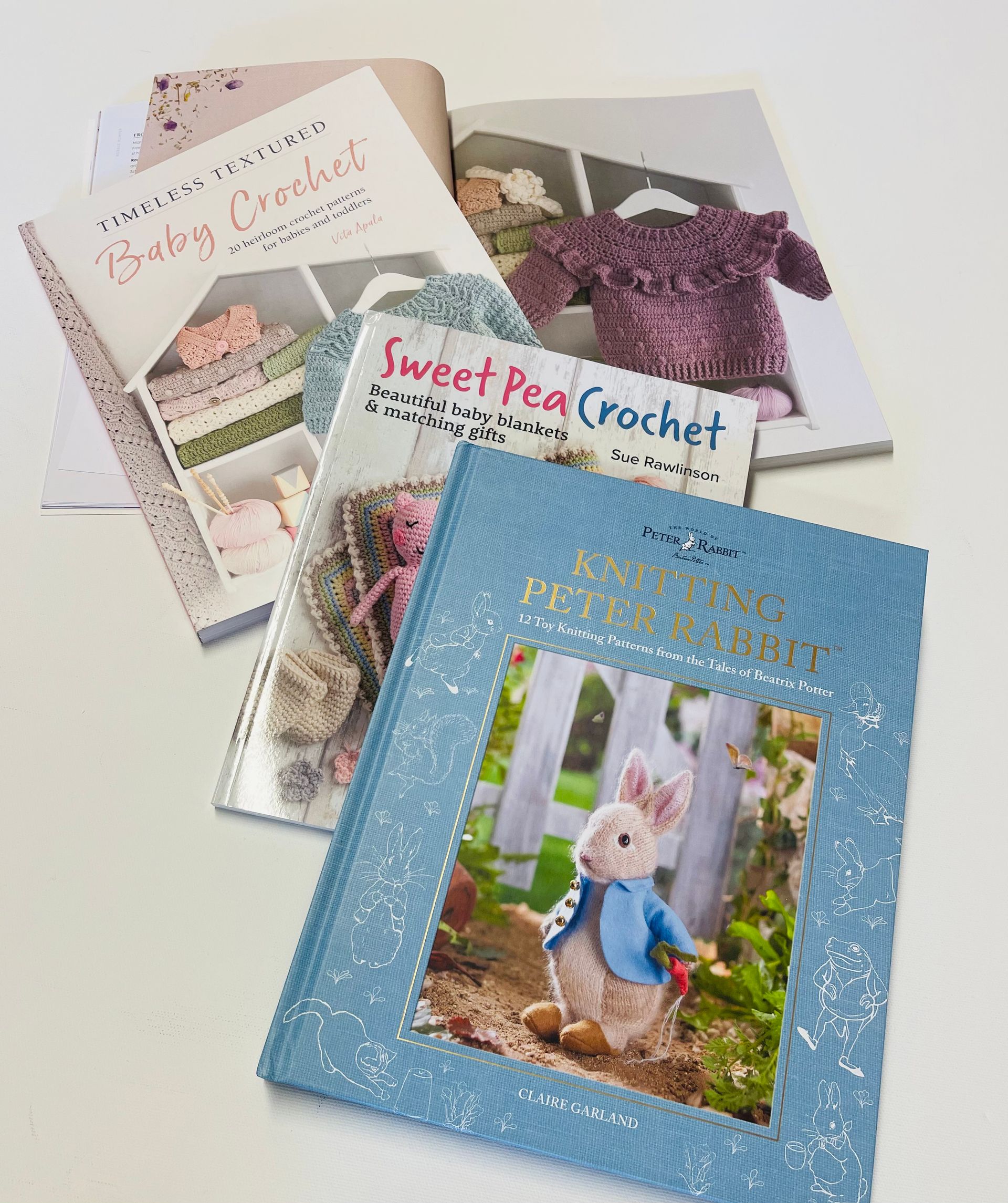 Three books are sitting on top of each other on a table including Peter Rabbit