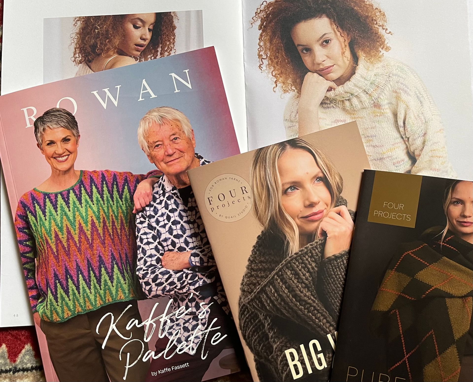 Rowan and Loro Piana knitwear pattern books featuring models wearing colorful sweaters and shawls.