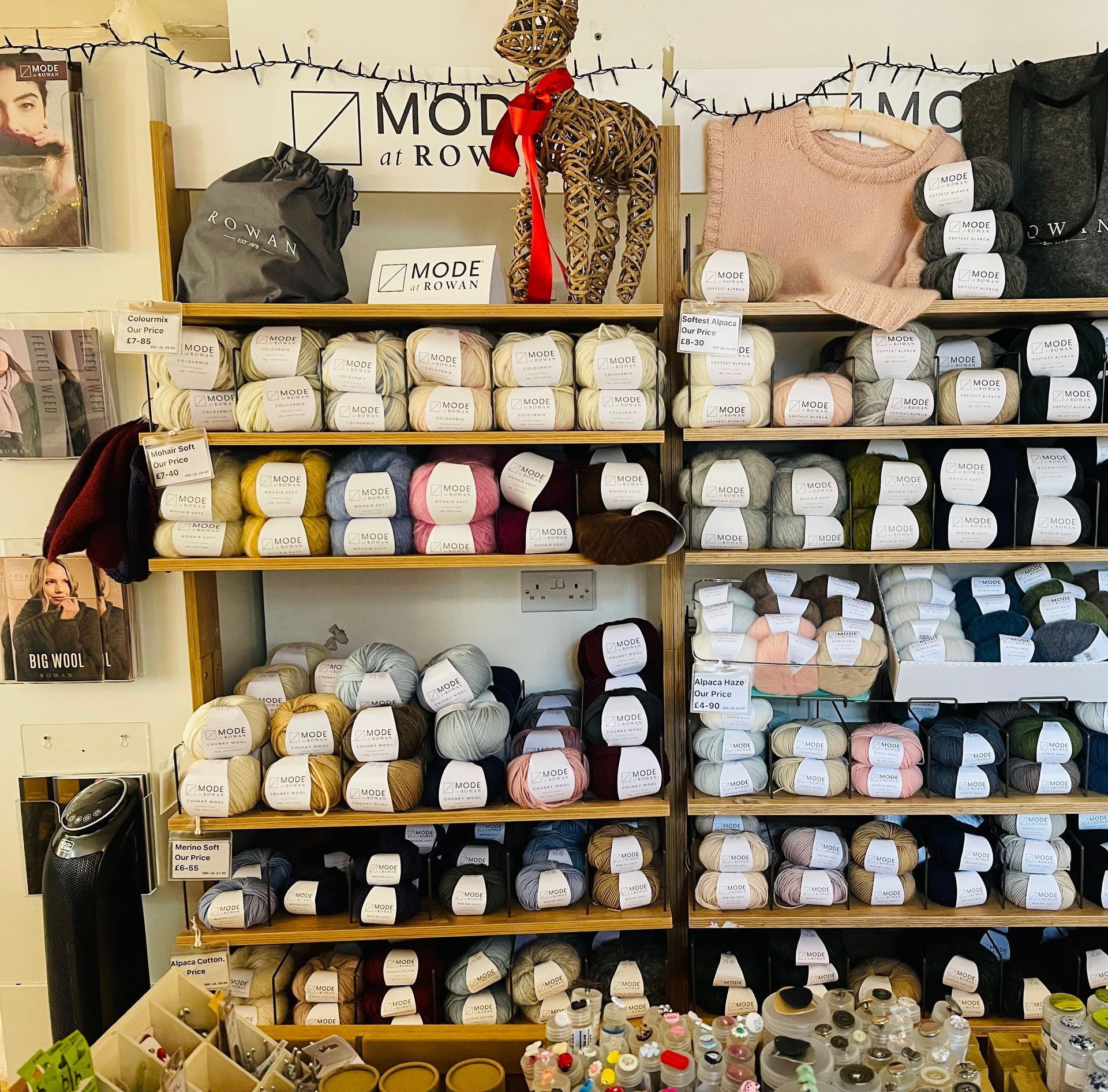 Shelves filled with colourful yarn balls and knitted garments in a craft store.