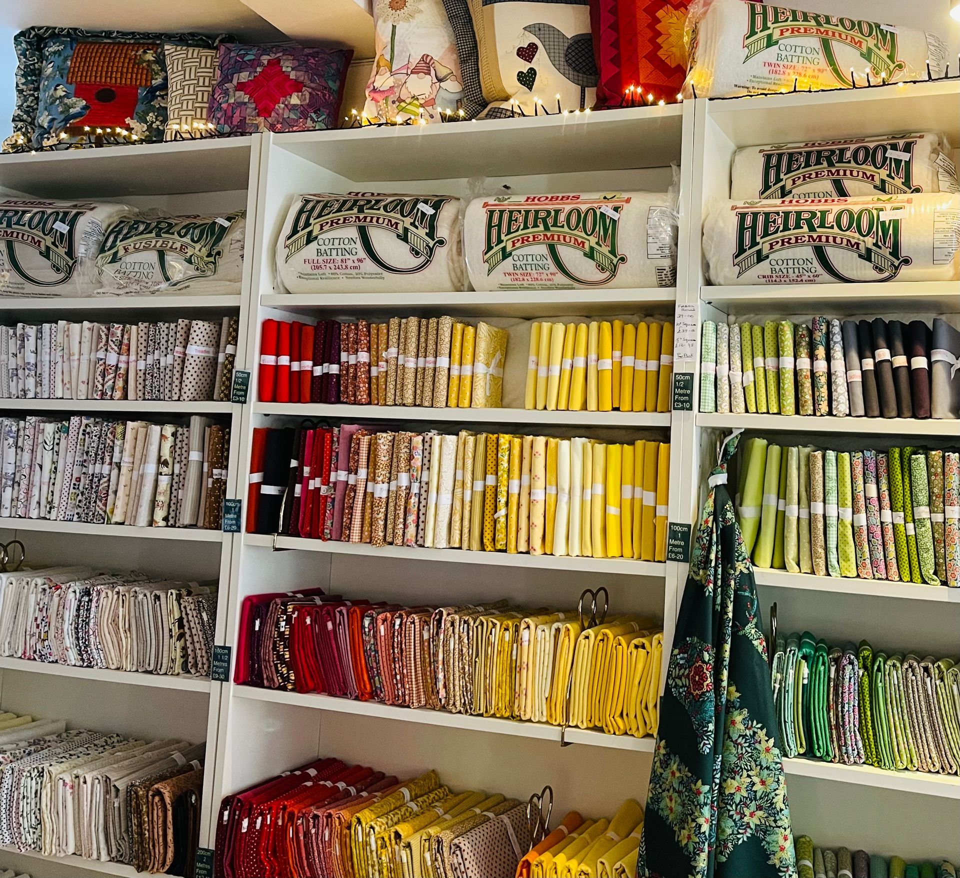 Shelves filled with colorful fabric, pillows, and textiles in a shop.
