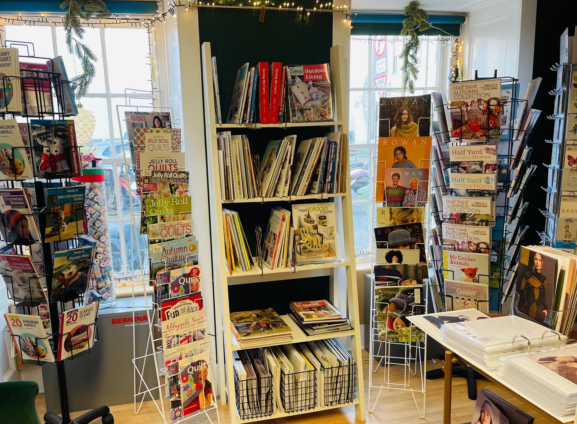Inside a store, manga comics displayed on shelving units and racks near a window.