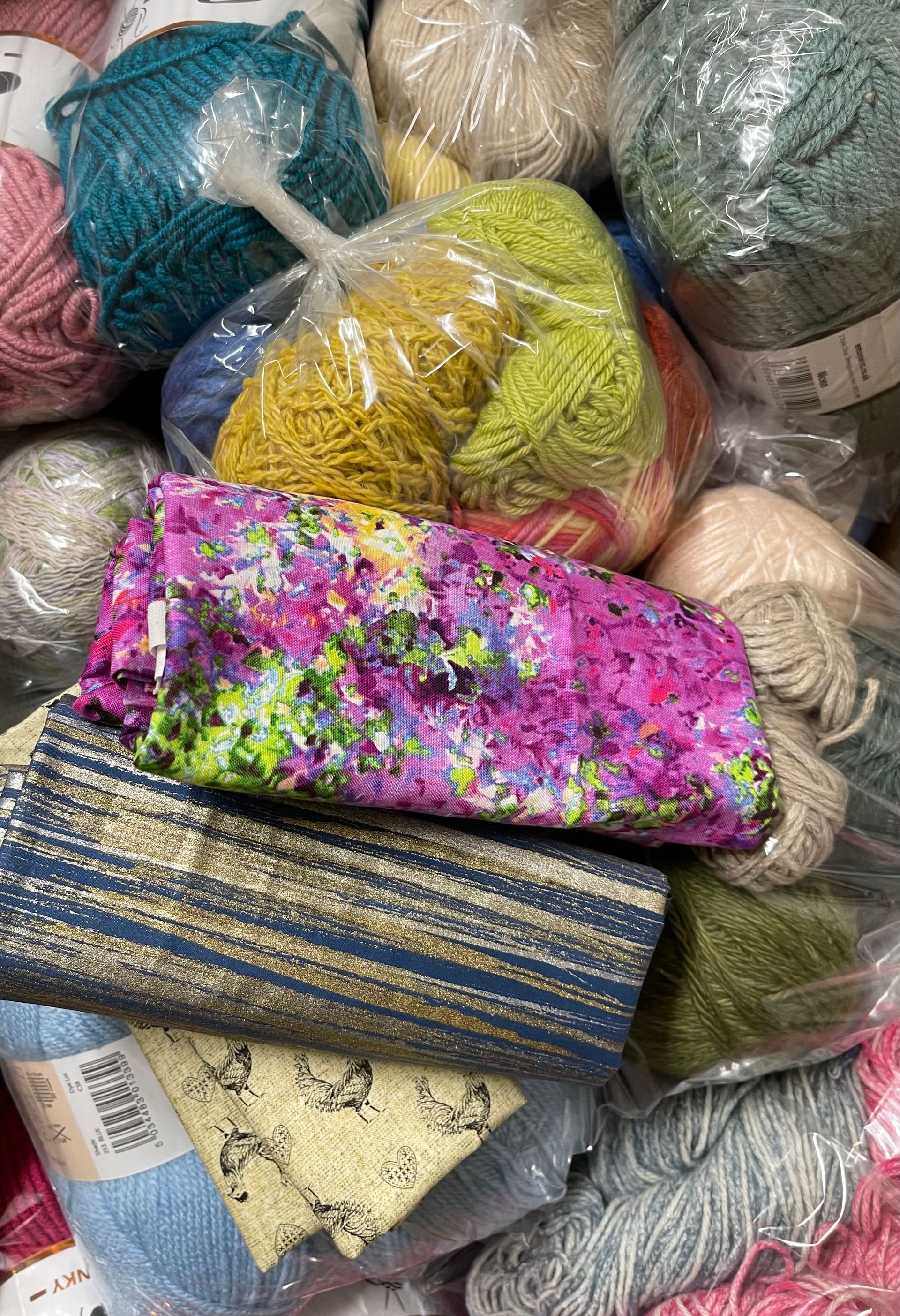 Pile of colorful yarn skeins and fabric scraps, various colors and textures.
