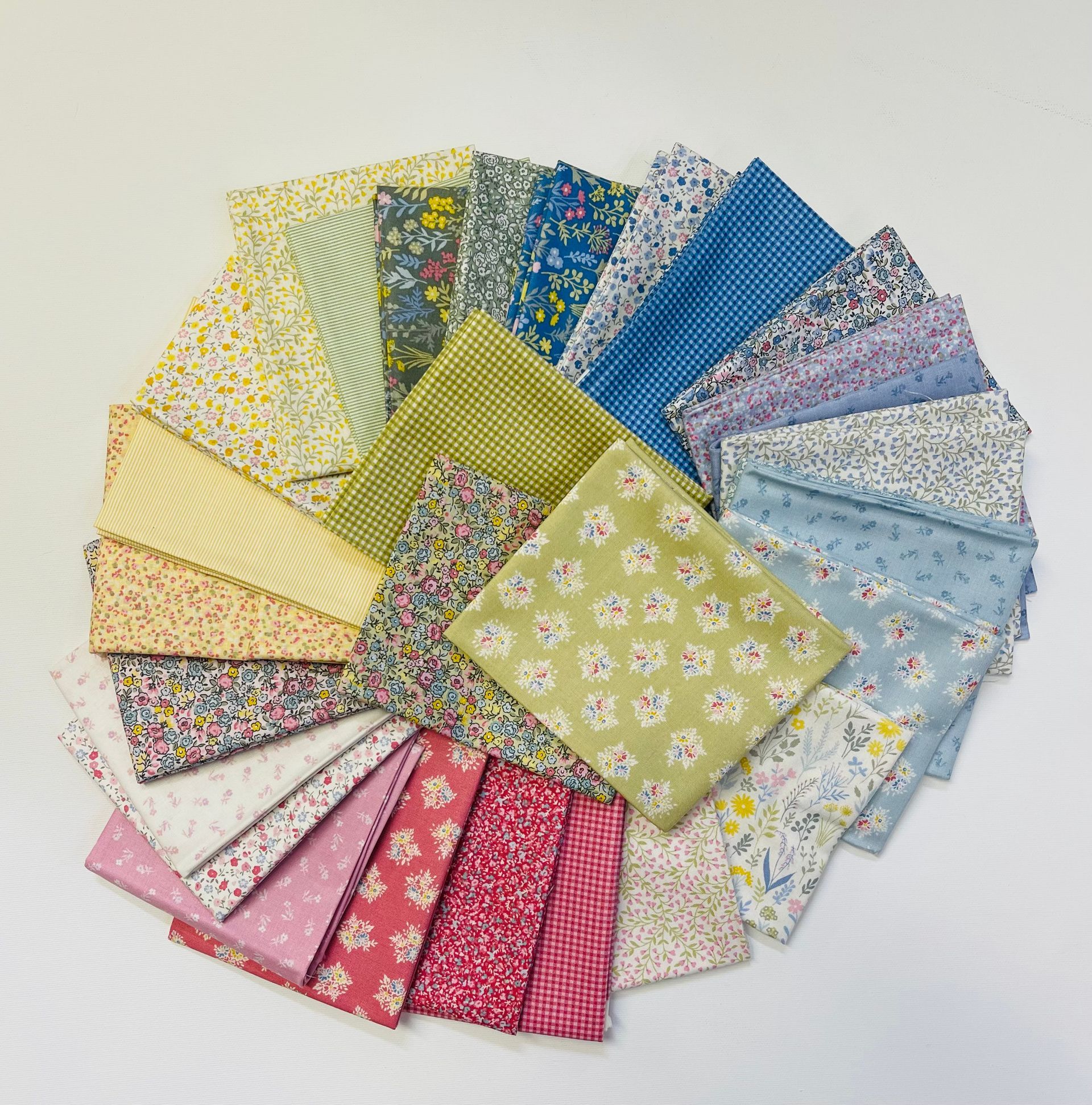 A circular arrangement of folded fabric squares in various floral, gingham, and striped patterns in yellow, blue, and red.