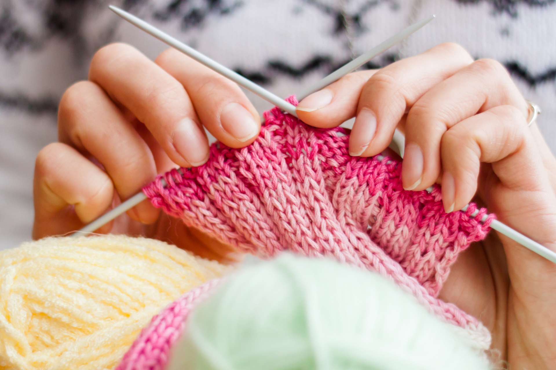 A close up of a person knitting with knitting needles.