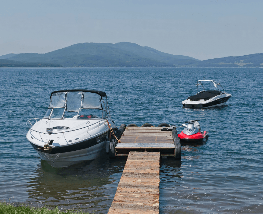 A boat is docked at a dock next to a jet ski.
